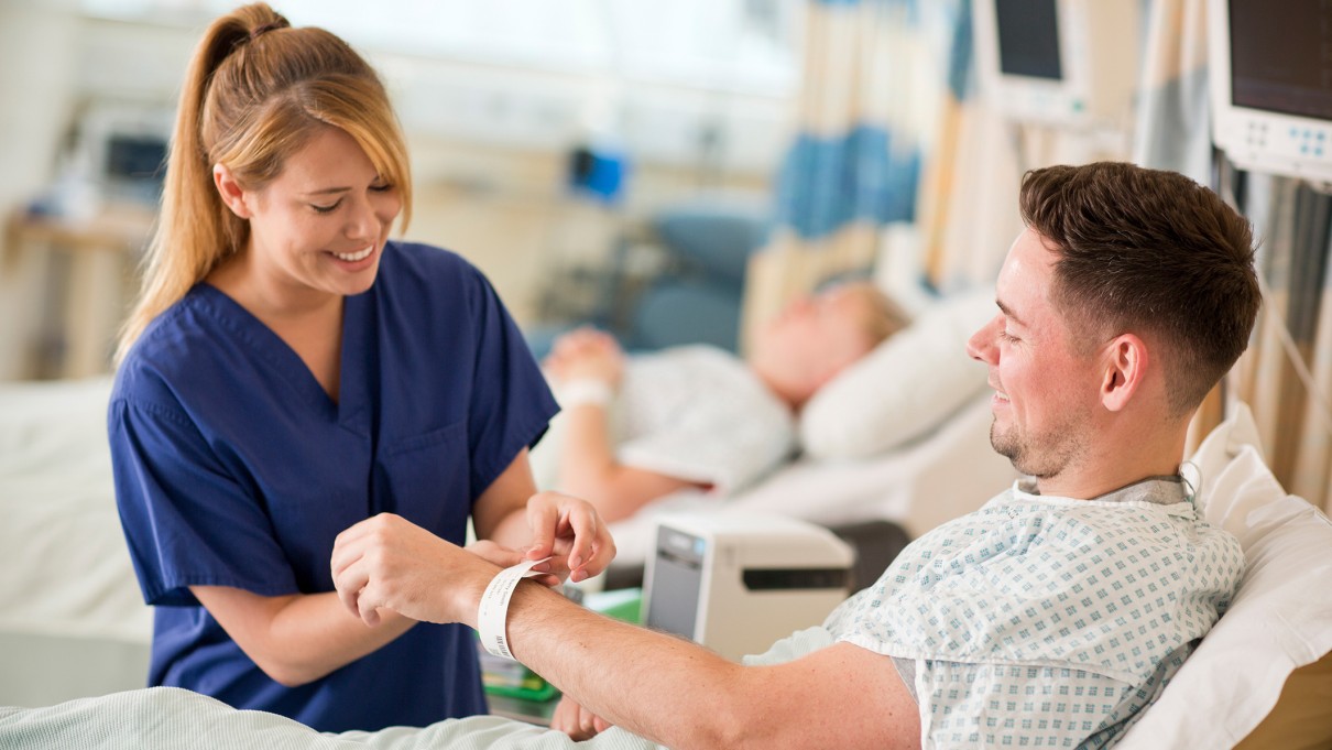Eine Krankenschwester legt einem Patienten ein Patientenarmband an. Eine Krankenschwester legt einem Patienten ein Patientenarmband an.